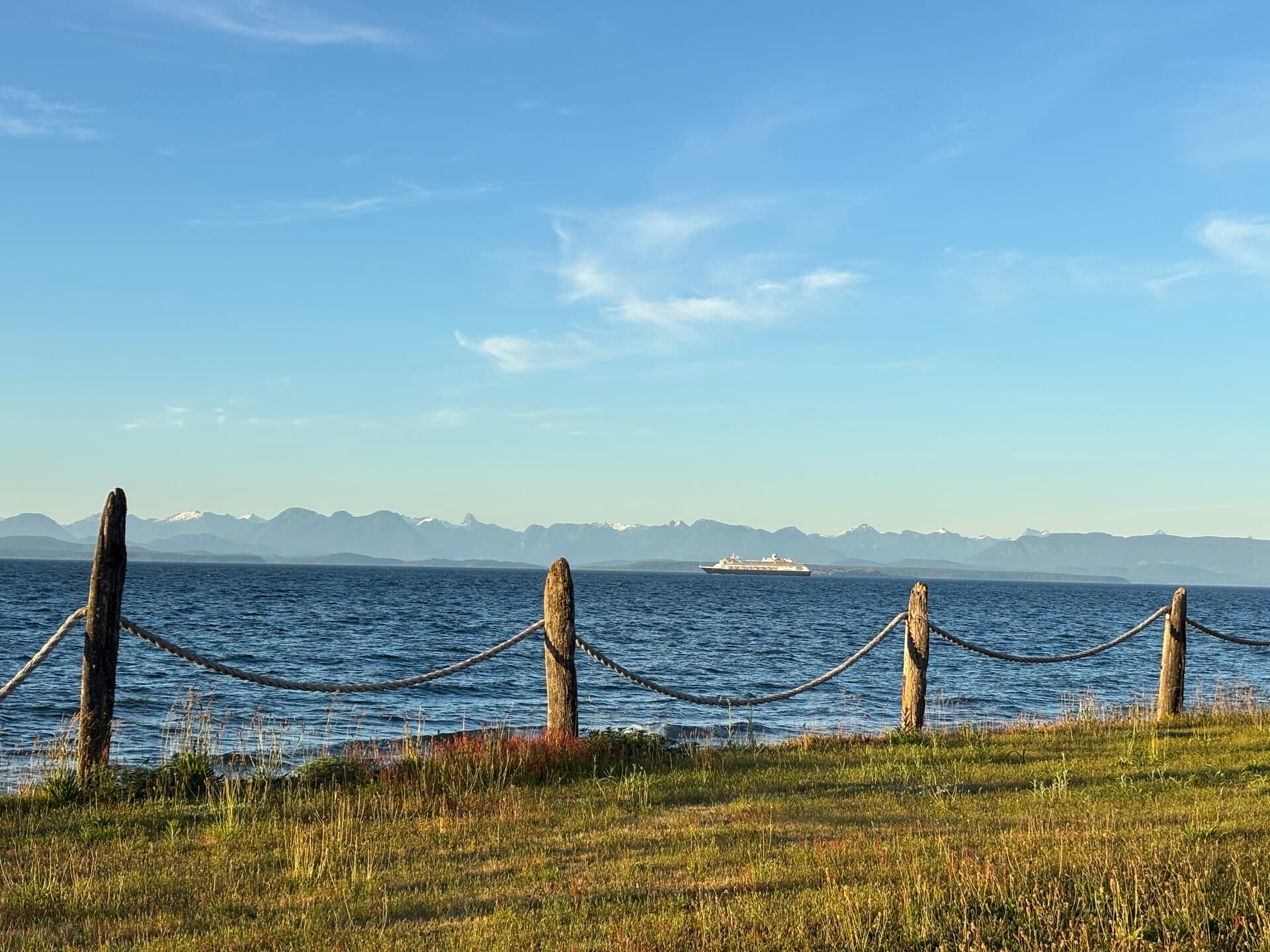 Resort lawn with rope fence, ocean, and mountain views