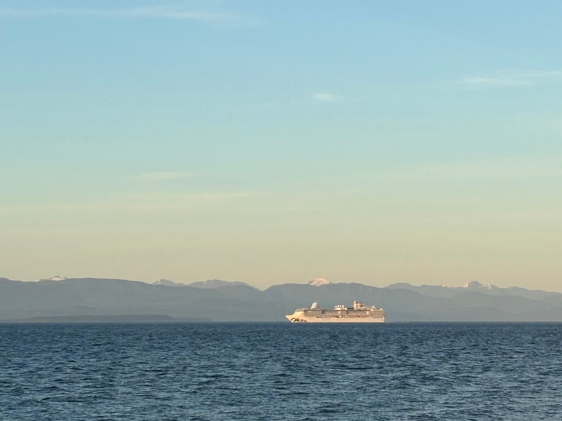 Cruise ship on the ocean with mountain backdrop