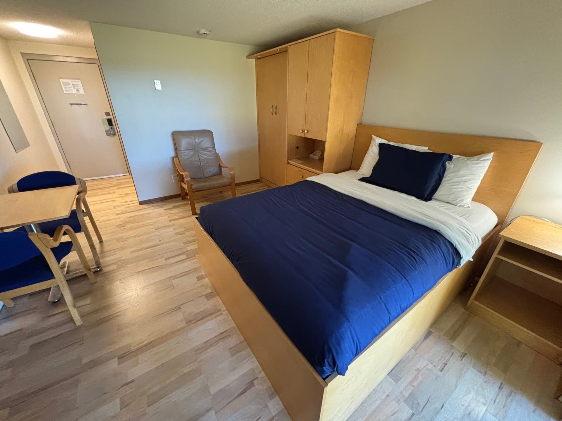 Queen bed with wardrobe, dining table, and armchair