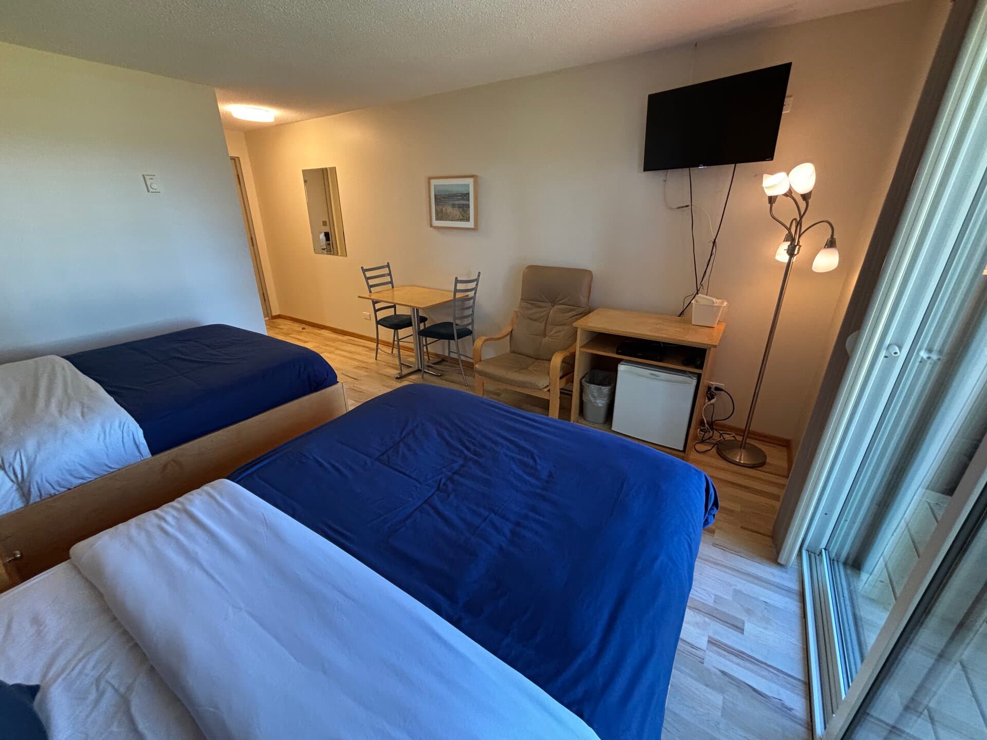 Beds with mini-fridge, TV, dining table, and balcony access