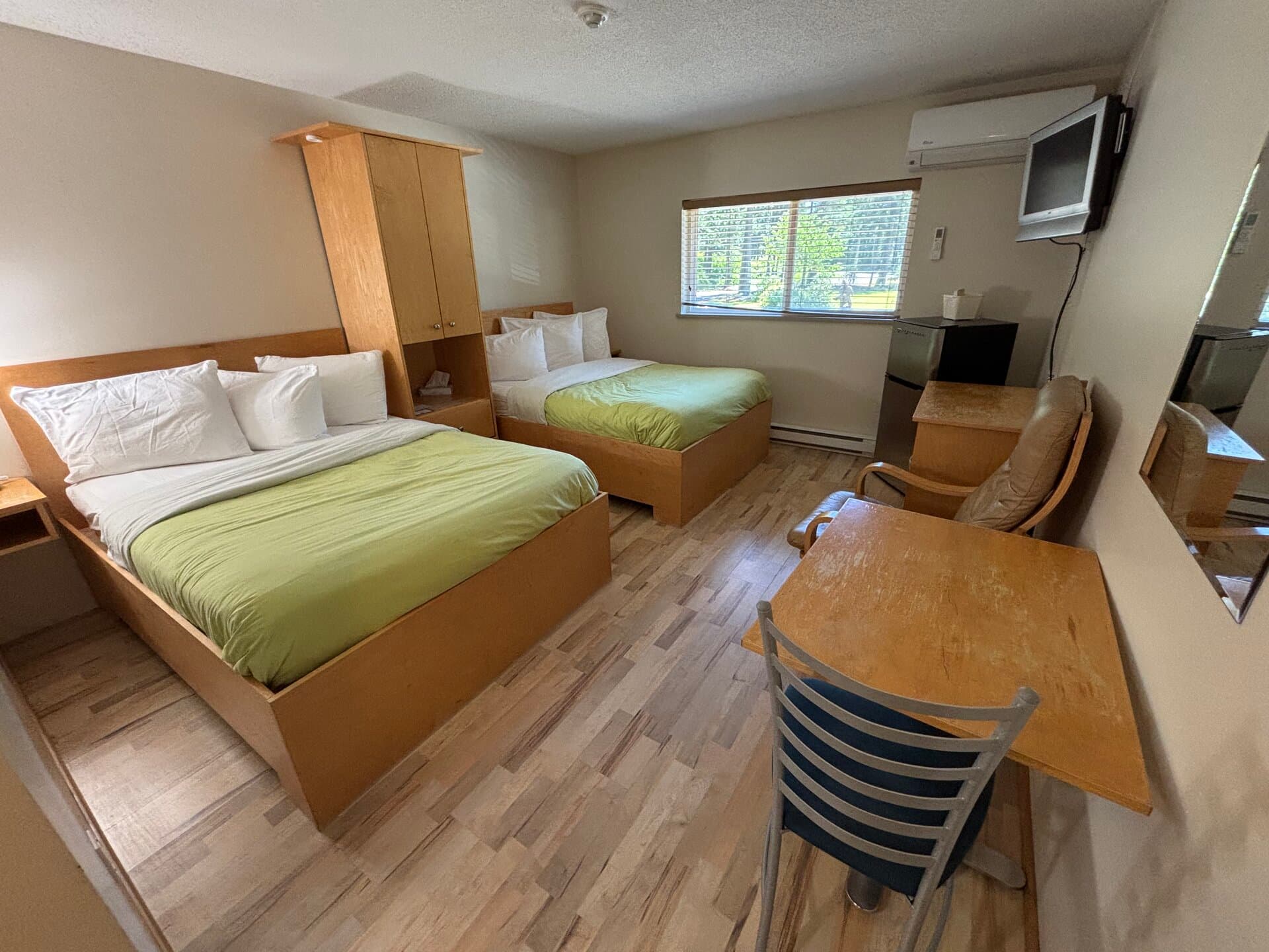 Standard Room with two double beds, dining table, and courtyard tree views