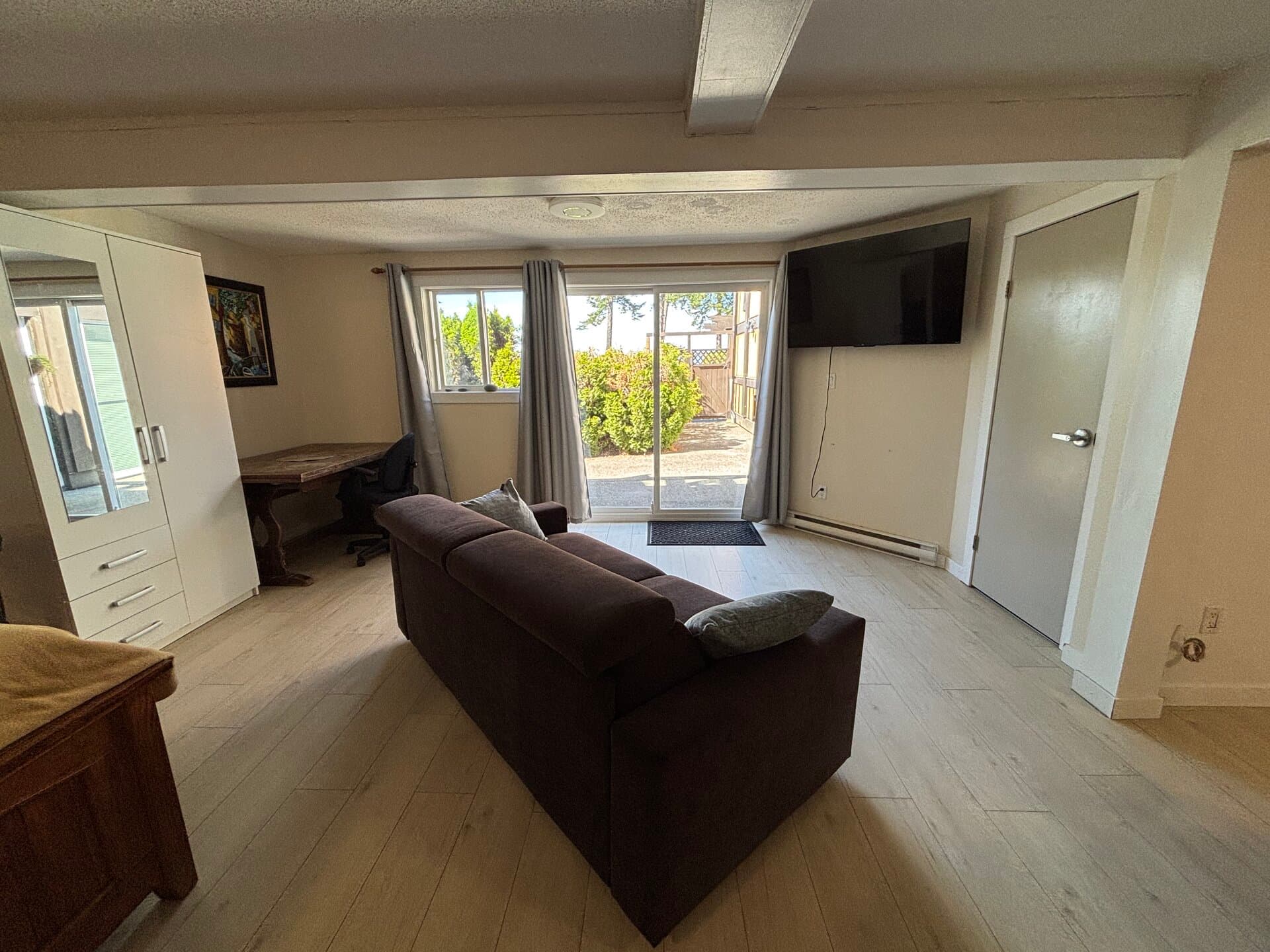 Comfortable sofa, workspace, television, and garden patio access