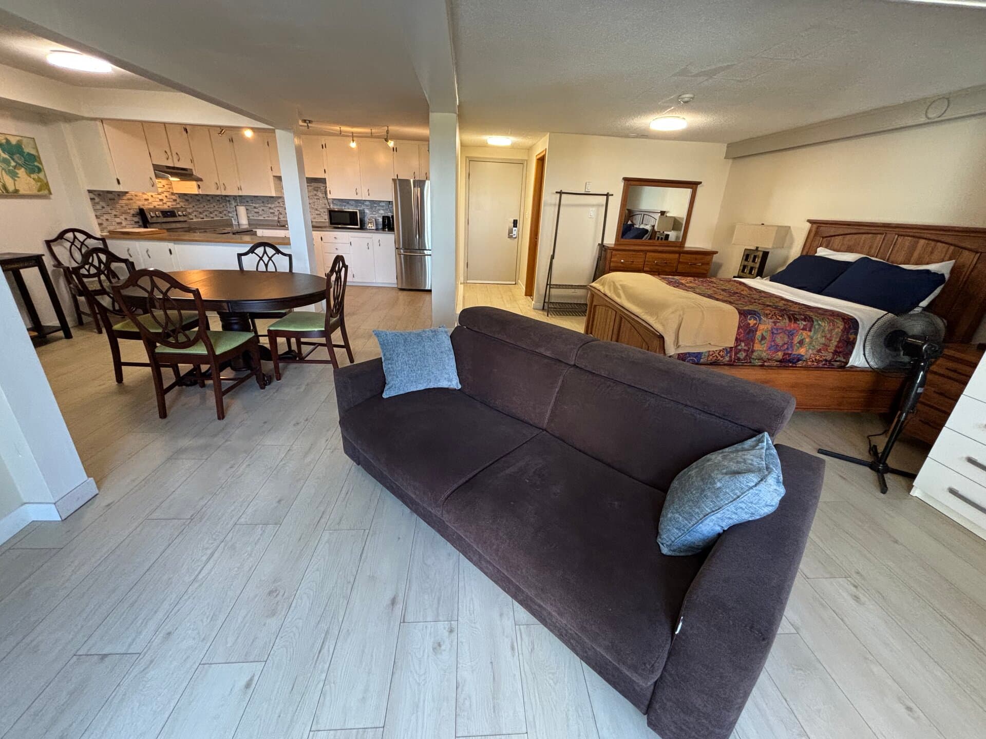 One-bedroom suite with queen bed, sofa, dining area, and full kitchen