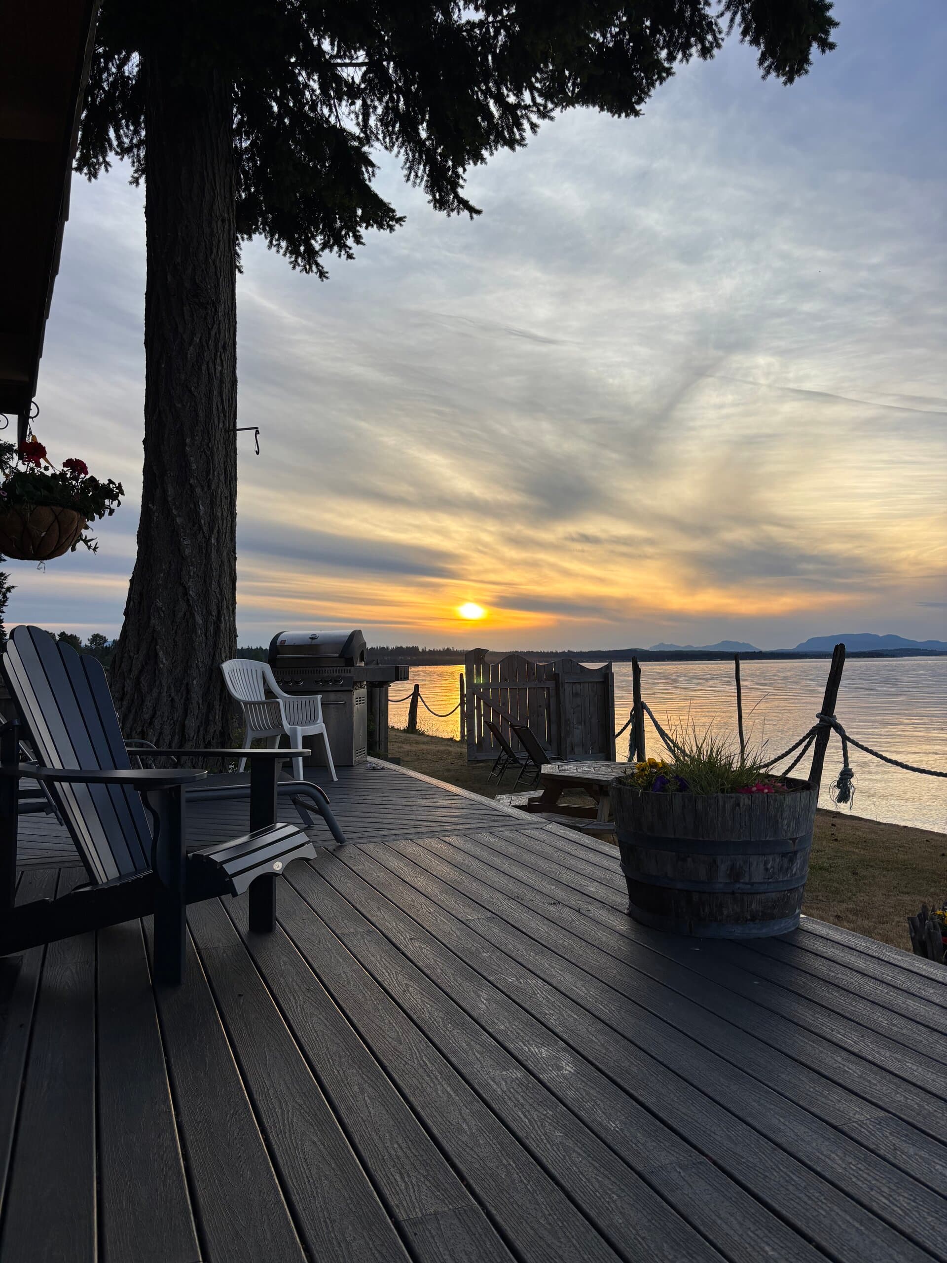 Deck at sunset with Adirondack chair, grill, and ocean horizon