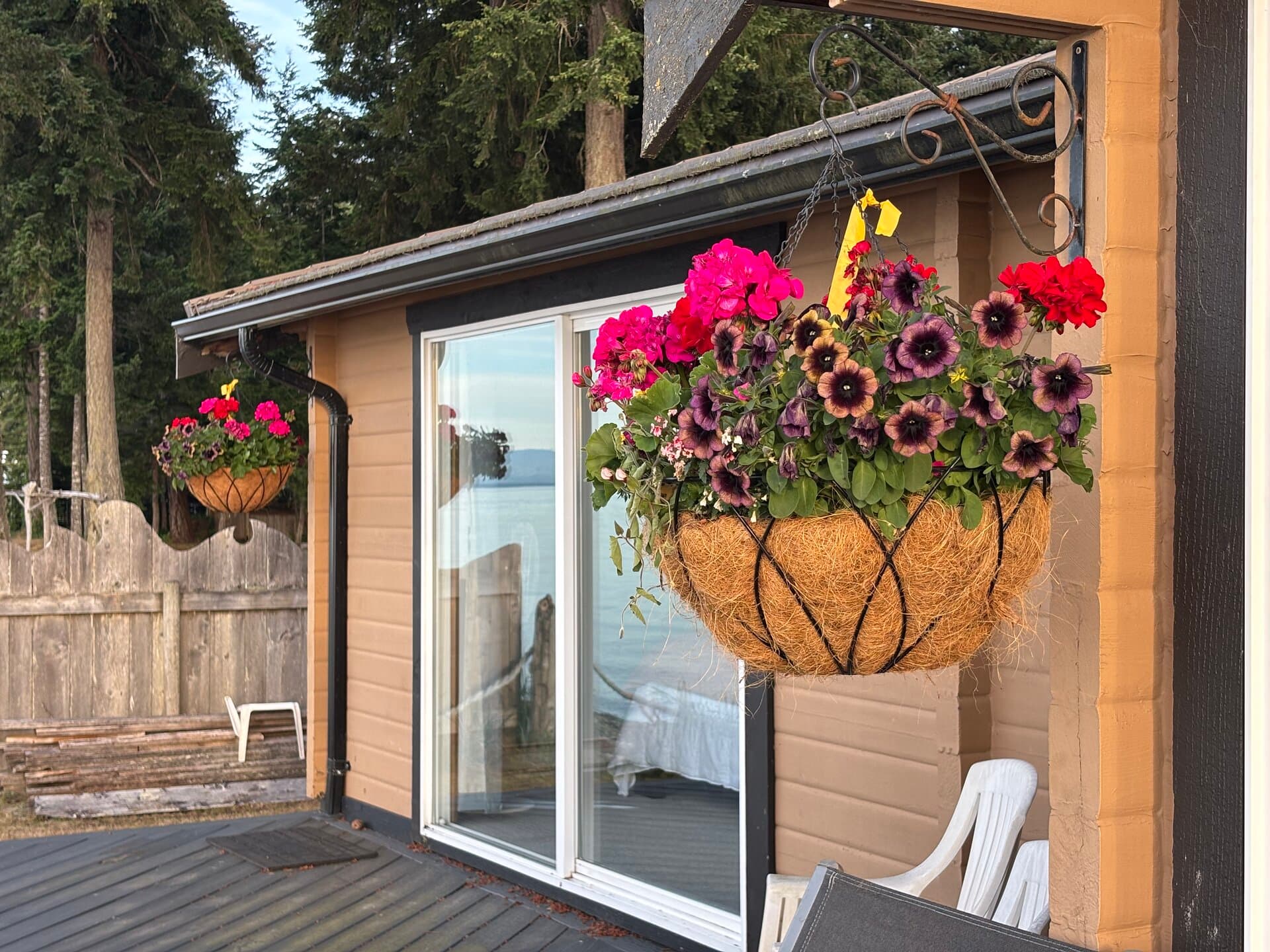 Exterior deck with flower baskets and ocean reflection in the glass