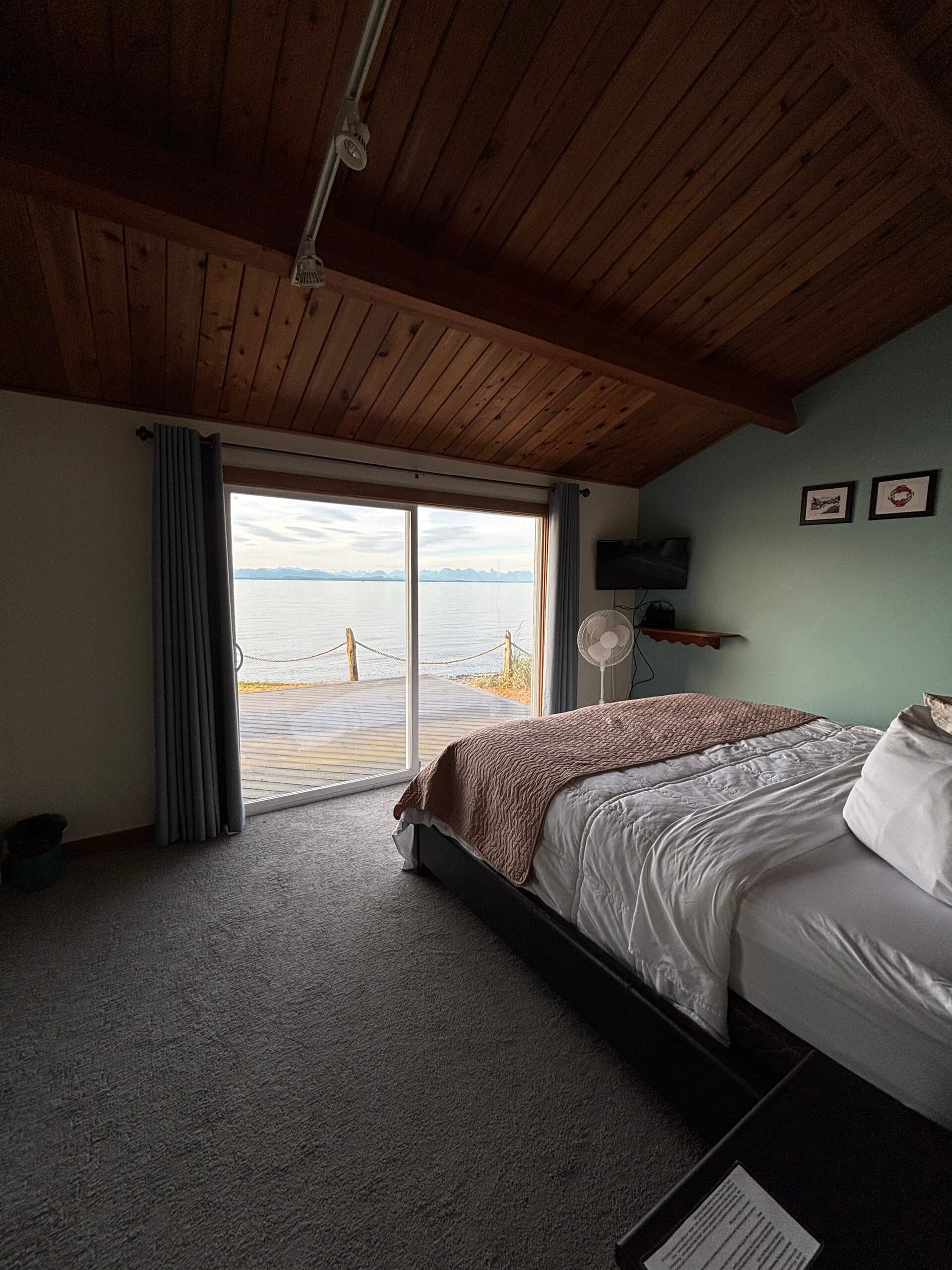 Queen bedroom with green accent wall and ocean-view deck access
