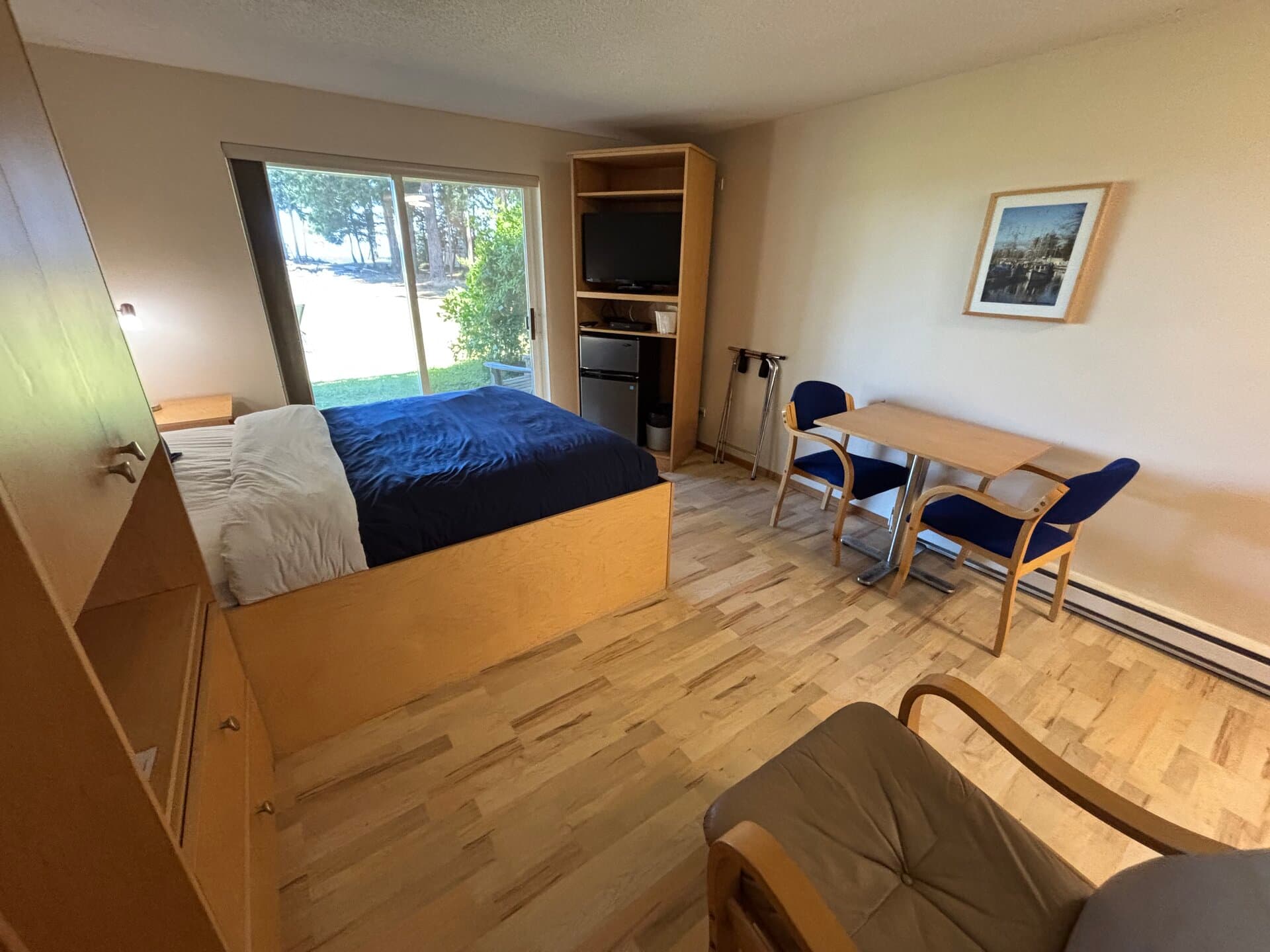 Queen bed with ocean-view sliding door, TV, and dining table