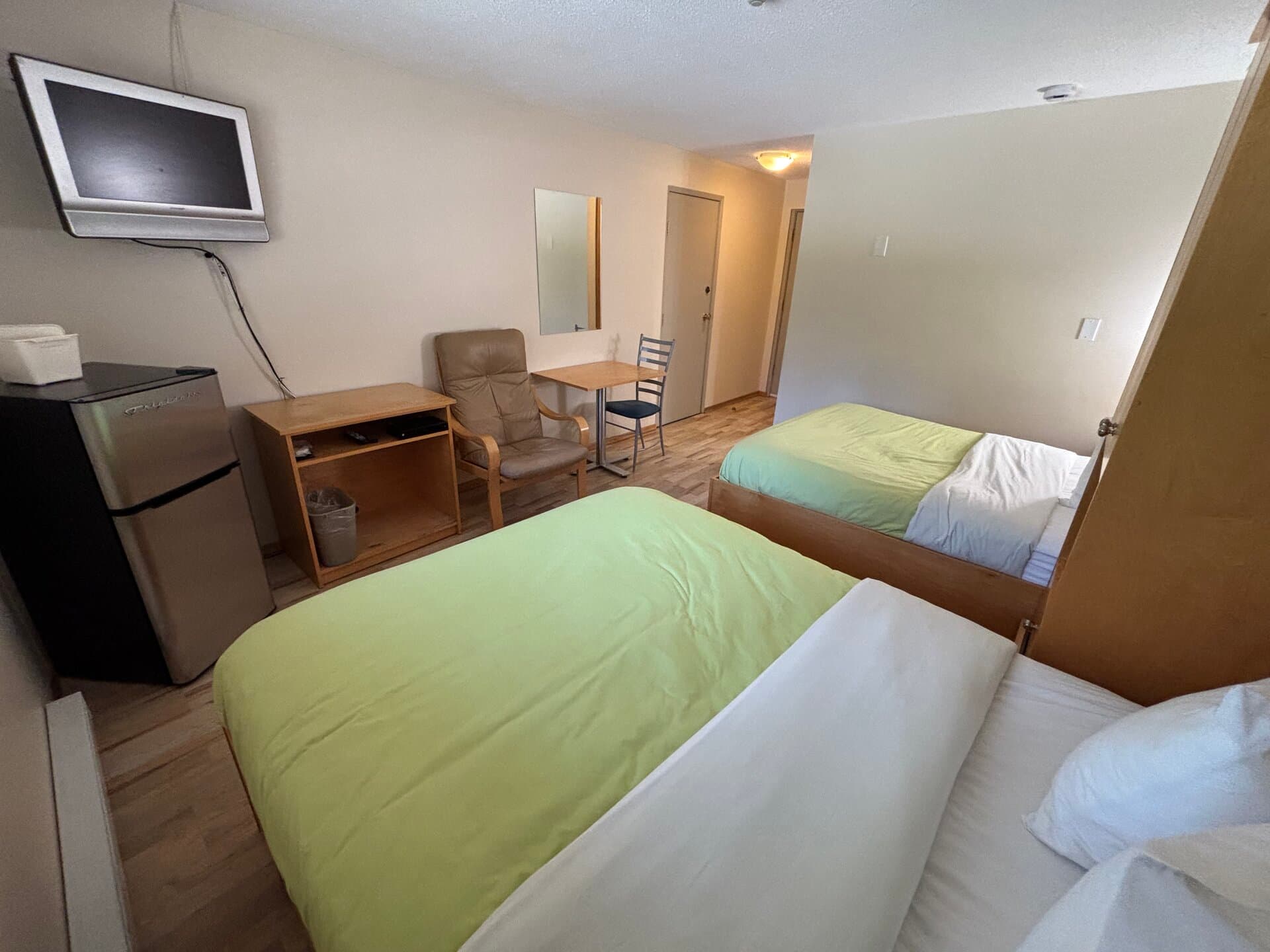 Two double beds with mini-fridge, TV, dining table, and armchair