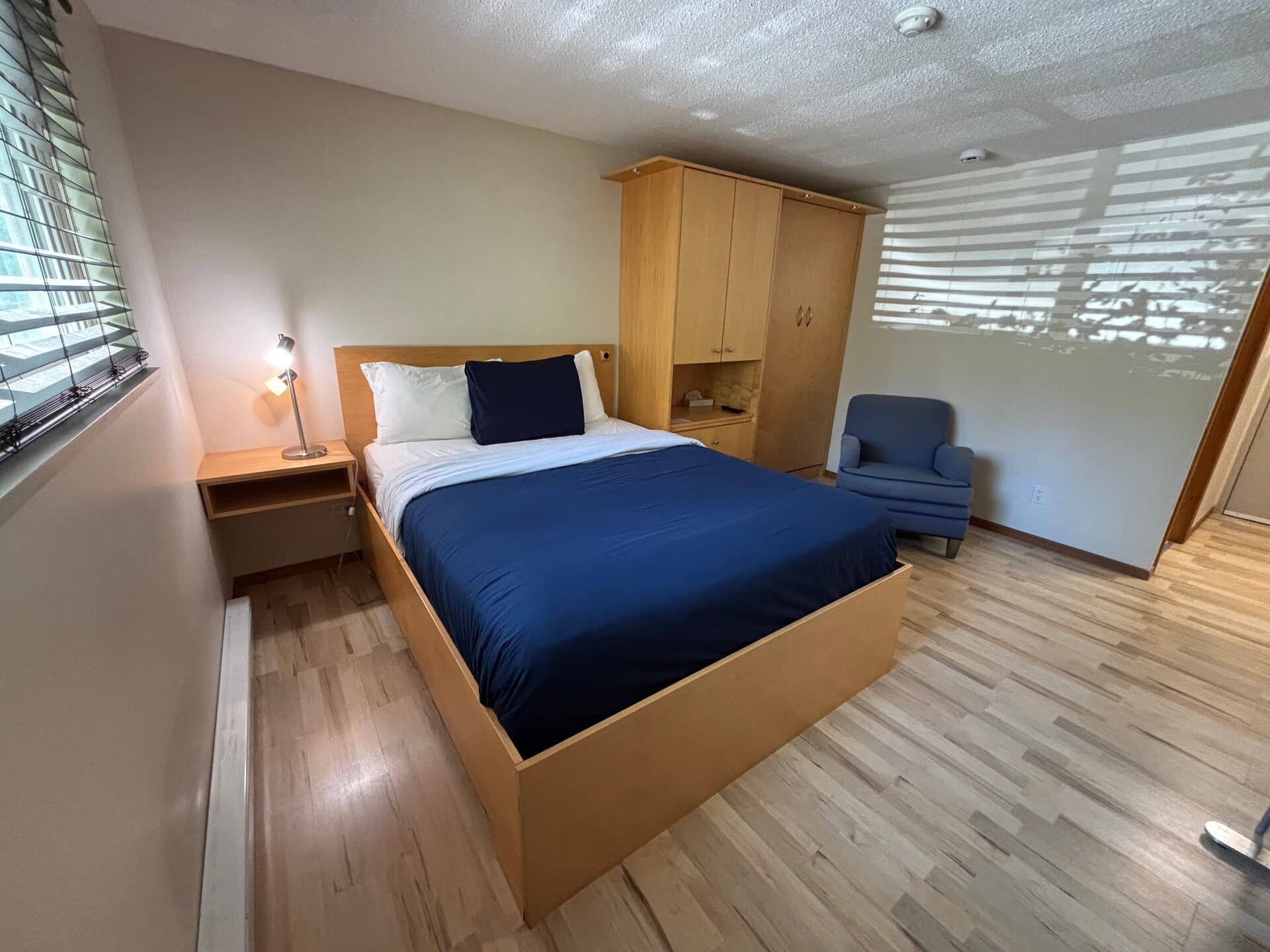 Queen bed with wardrobe, armchair, and non-view windows