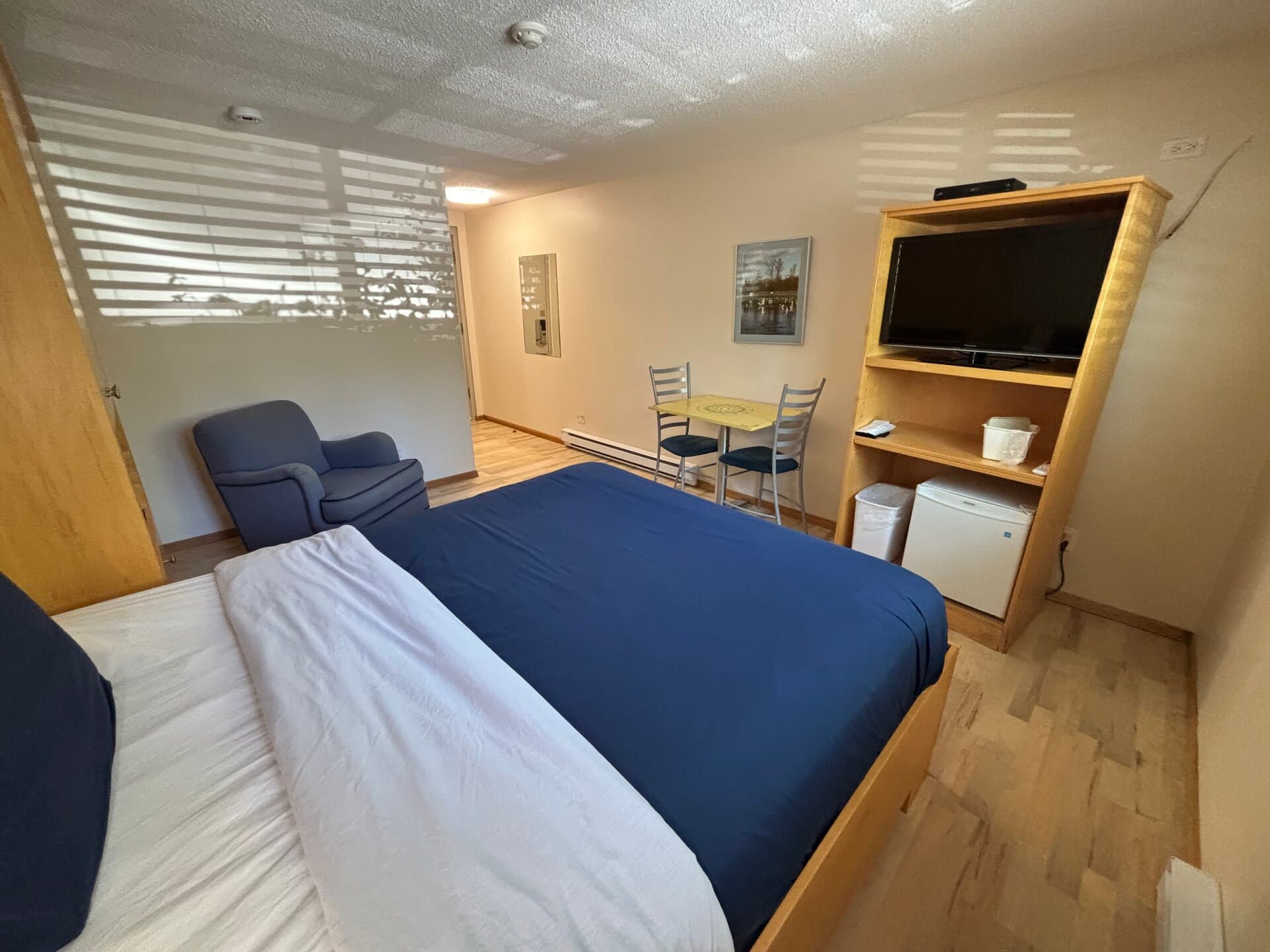Queen bed with mini-fridge, TV, dining table, and Murphy cabinet