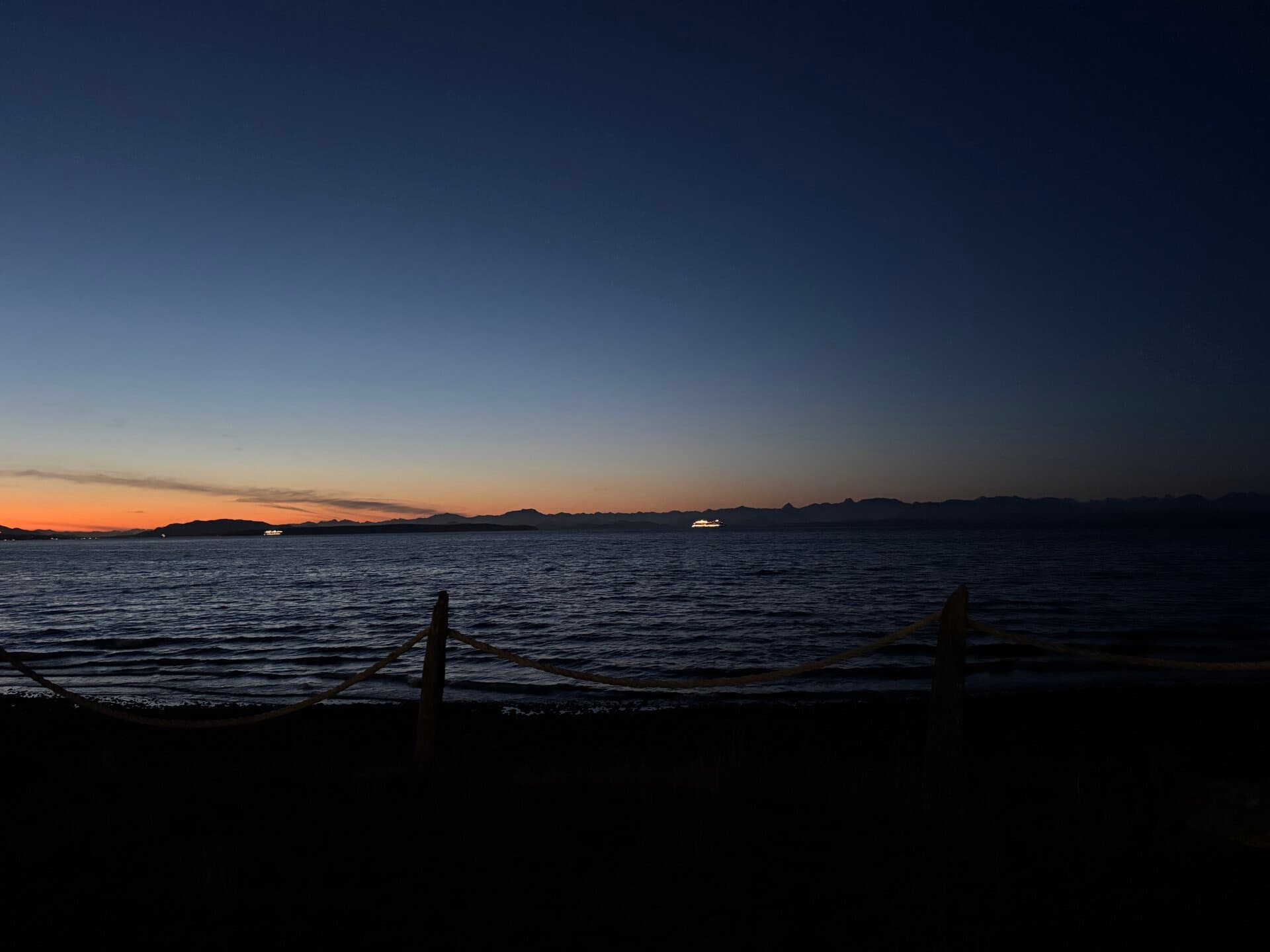 Twilight beach with rope fence and mountain silhouette