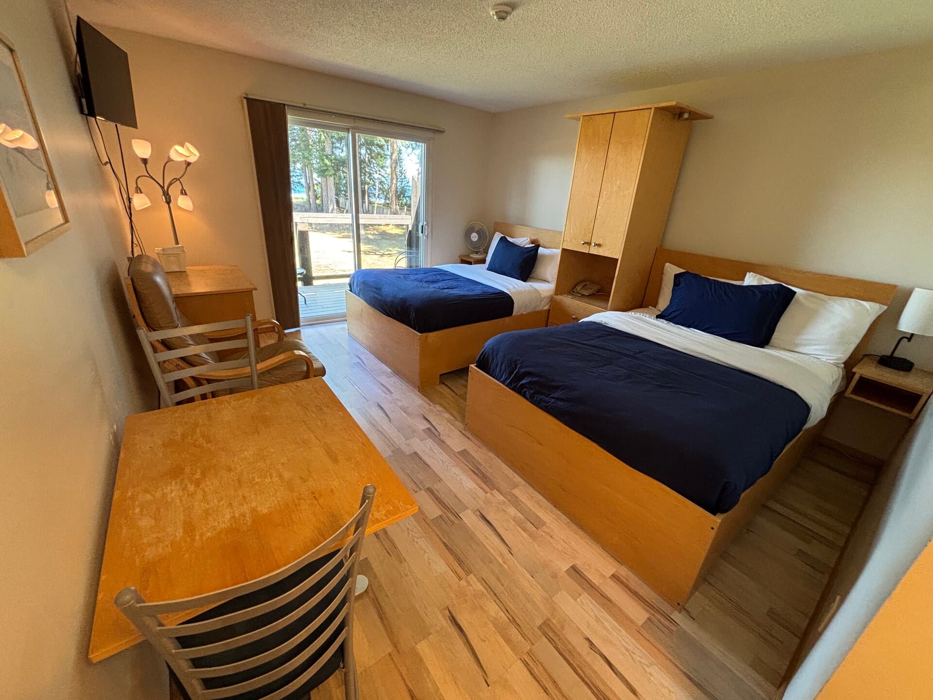 Two double beds with dining area, lounge chair, and balcony ocean views